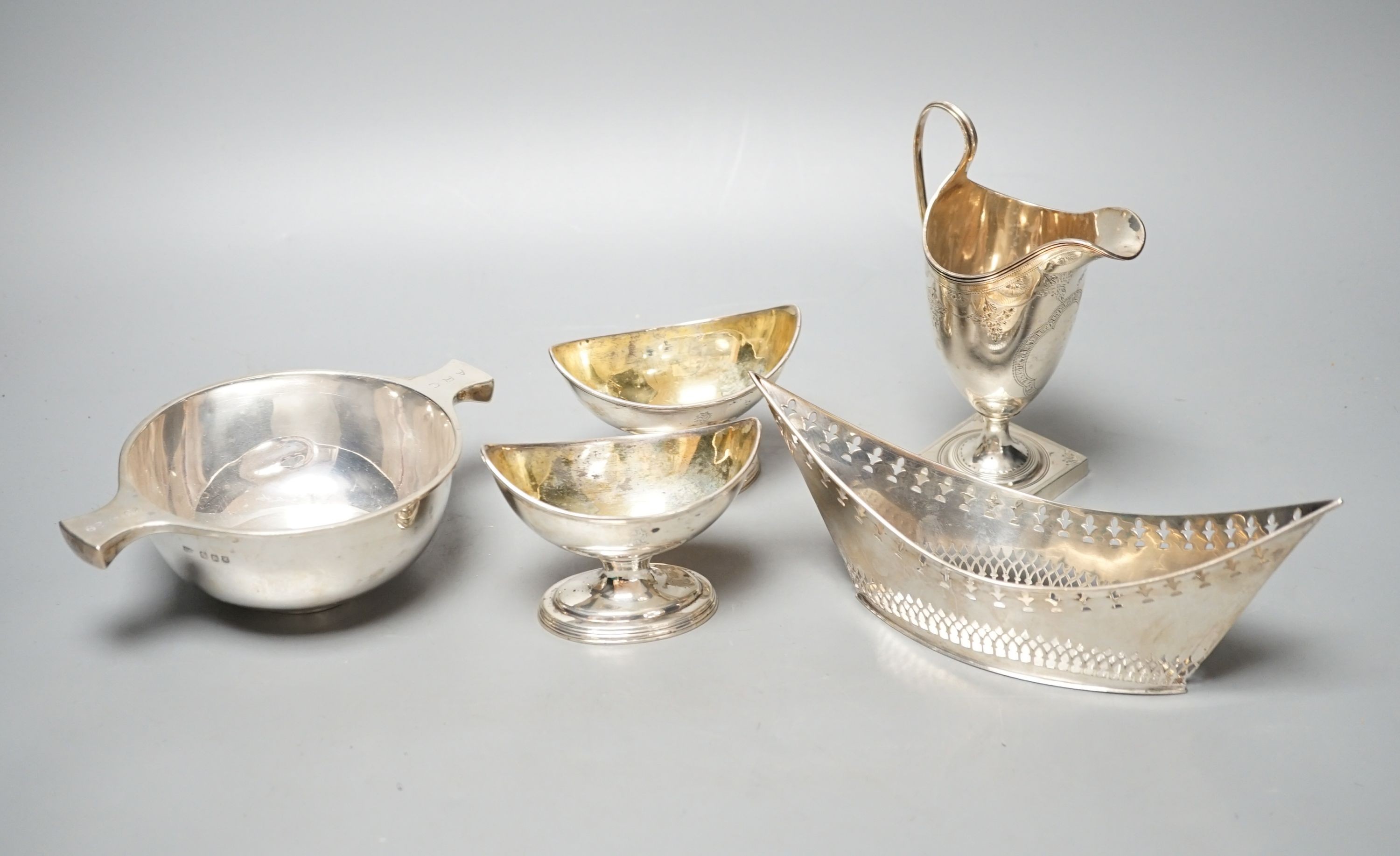 A mixed collection of silver to include a Scottish quaich, a pair of George III boat shaped salts, a George III silver helmet shaped cream jug and a pierced boat-shaped bowl, 17oz.